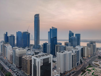 Modern buildings in city against sky during sunset