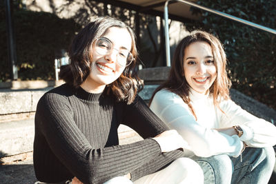 Portrait of smiling sisters sitting on steps