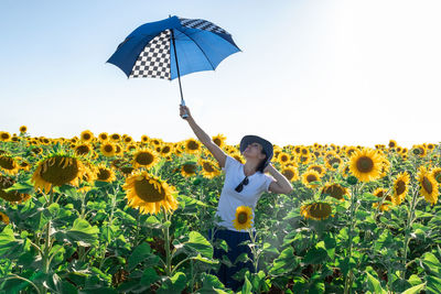 Full length of woman holding sunflower on field against sky