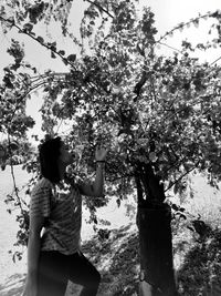 Side view of woman standing by tree