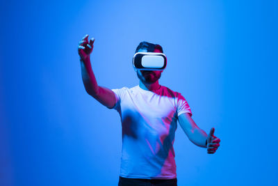 Young man wearing vr headset against blue background