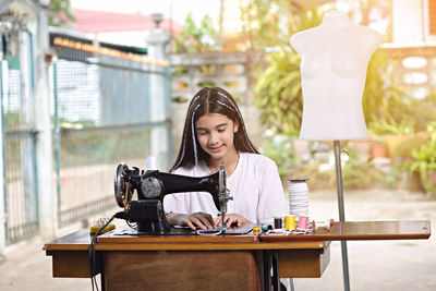 Girl stitching with sewing machine in workshop