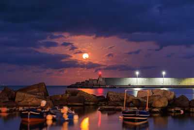 Illuminated bridge over river against sky at sunset