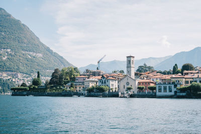 Buildings by river against sky