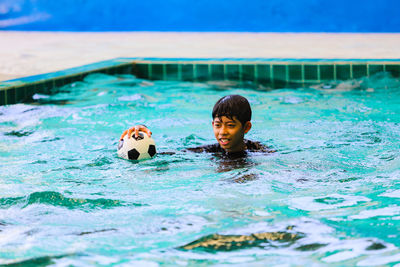 Portrait of boy with ball in swimming pool
