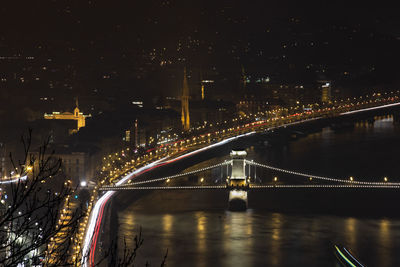 Illuminated bridge over river in city at night