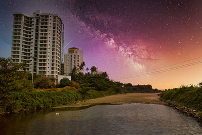 Scenic view of trees and buildings against sky at night