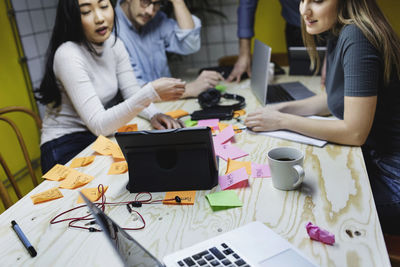 Four people using digital tablet at desk in creative office