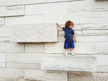 Full length of smiling girl standing against wall