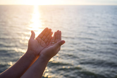 Cropped image of woman with cupped hands against sea