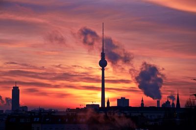 Tower and buildings against sky during sunset