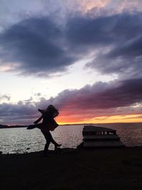 Woman standing on beach against sky during sunset