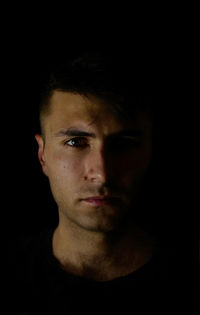 Close-up portrait of young man against black background