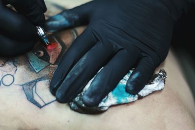 Cropped hands of male artist tattooing on customer