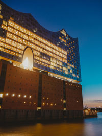 Low angle view of illuminated buildings against blue sky