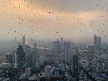 Cityscape seen through wet glass window during rainy season