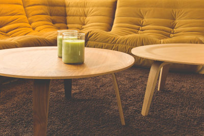 Close-up of drinks on table by sofa