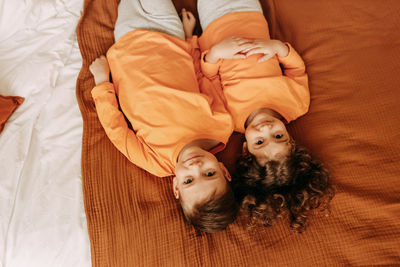 Funny happy kids brother and sister in pajamas playing having fun in a cozy bedroom at home