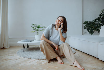 Smiling young girl talking on smartphone at home