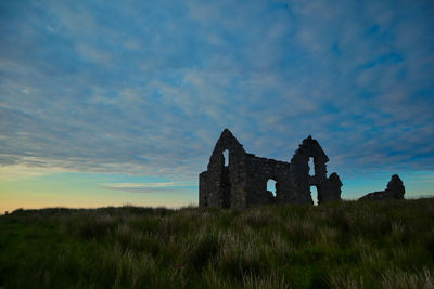 Old ruin building on field against sky