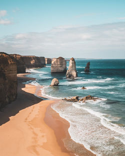 Rock formation on beach against sky