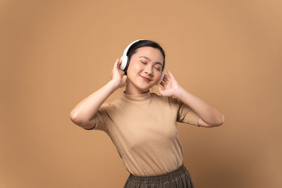 Portrait of young woman standing against yellow background