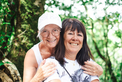 Portrait of smiling friends standing against trees