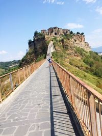 Man on footbridge against sky