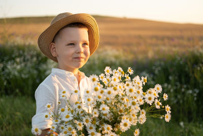 Cute boy holding bouquet standing on field