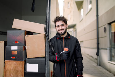 Portrait of confident delivery man with boxes in truck