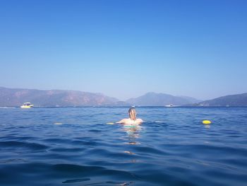 Man swimming in sea against clear sky