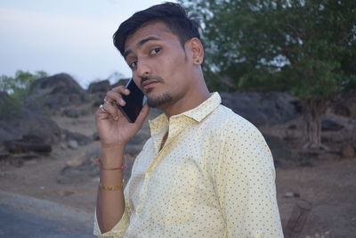 Portrait of young man talking on phone while standing on road