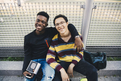 Portrait of smiling young men sitting against net