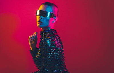 Young woman with shaved head against pink background