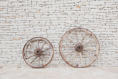 Two vintage wooden wheels. antique masonry in beige shades. textured background from natural stone.