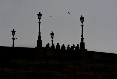 Low angle view of silhouette birds on street against sky