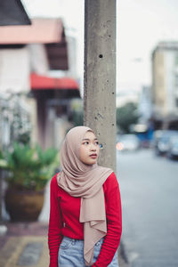 Young woman looking away while standing on street