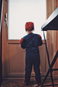 Rear view of boy standing against door