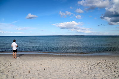 Rear view of man on beach against sky