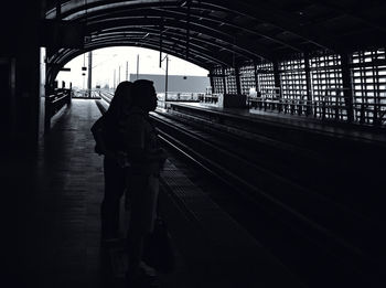 Rear view of people standing at railroad station