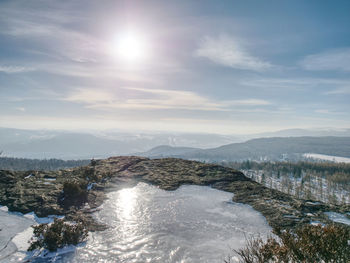 Rocky hill covered by dangerous ice during winter sunset. sun in clear blue sky