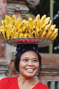 Close-up of happy female vendor with bananas on head