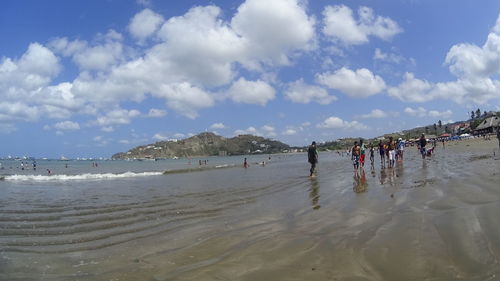 Panoramic view of people on beach against sky