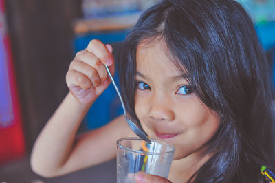 Close-up portrait of girl drinking juice while sitting in restaurant