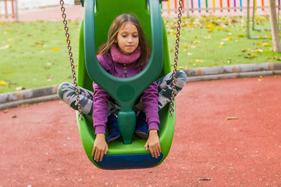 Girl sitting on swing at park