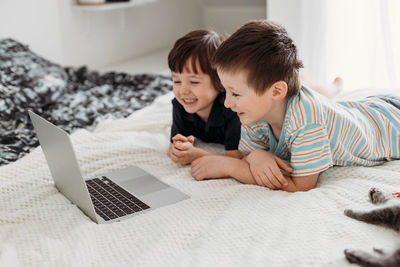 Cute kids lying on bed looking at laptop