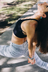 Midsection of woman with arms raised in a park doing yoga 