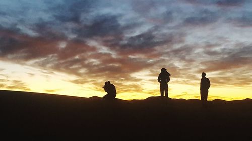 Silhouette people standing against sky during sunset