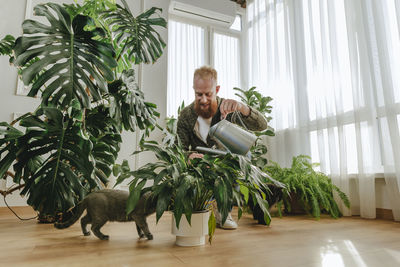 Smiling man watering plants at home