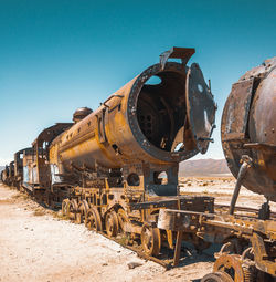 Abandoned train on railroad track against blue sky during sunny day